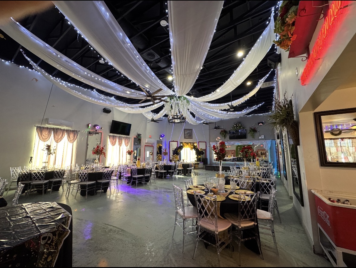 Elegant party hall interior with warm lighting, balloon arches, and a polished dance floor